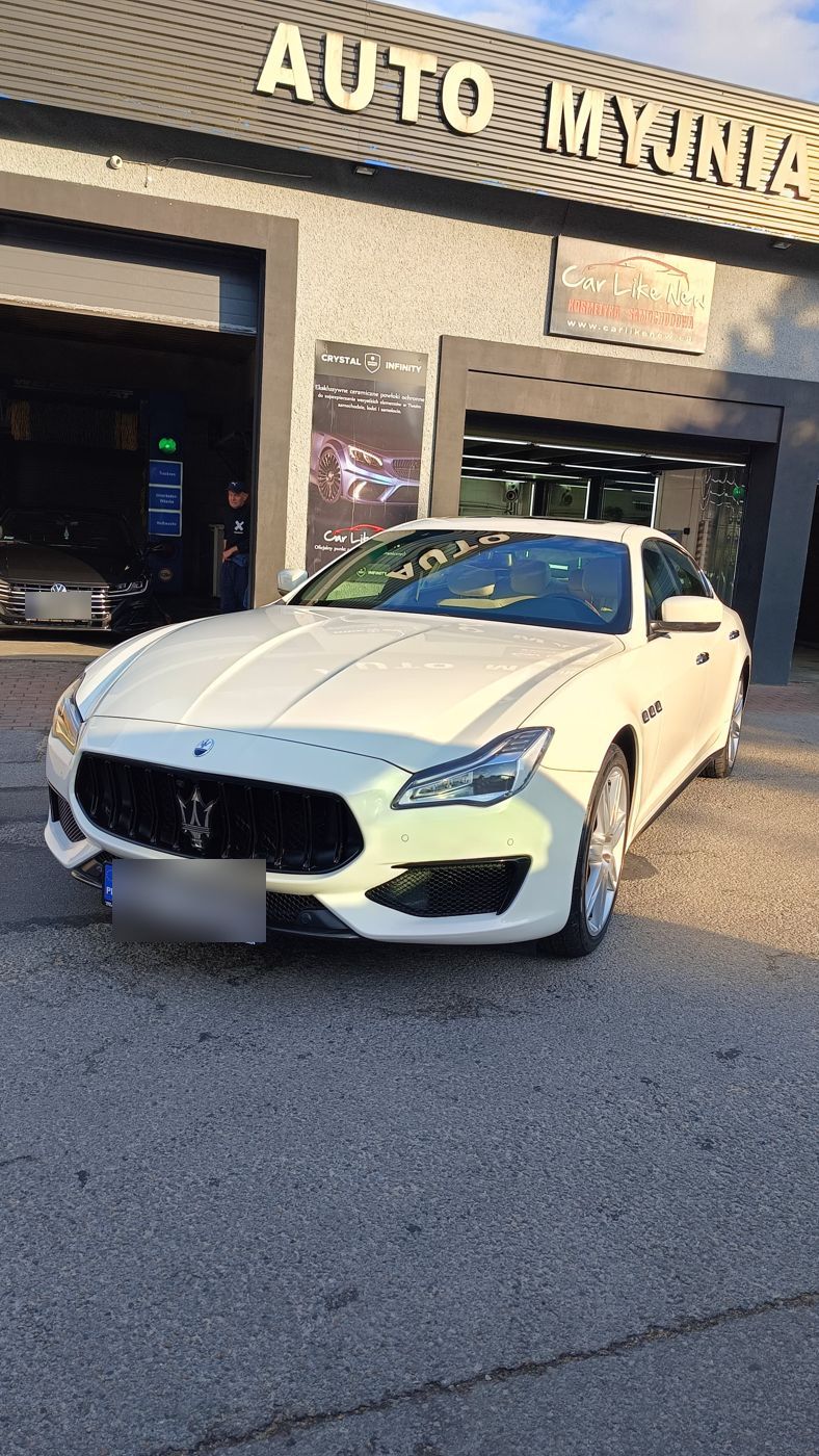 Biały Maserati przed budynkiem myjni